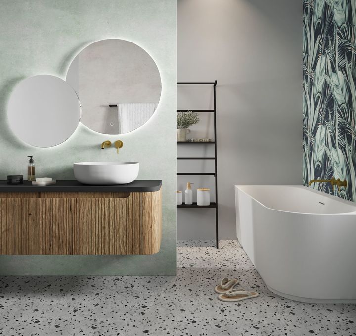 Badkamer met terrazzo vloer, houten meubel en goudkleurige kraan boven ronde waskom