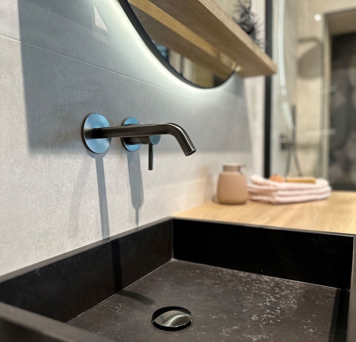 Moderne wandkraan gecombineerd met zwart wastafelblad en lichtgrijze tegelwand