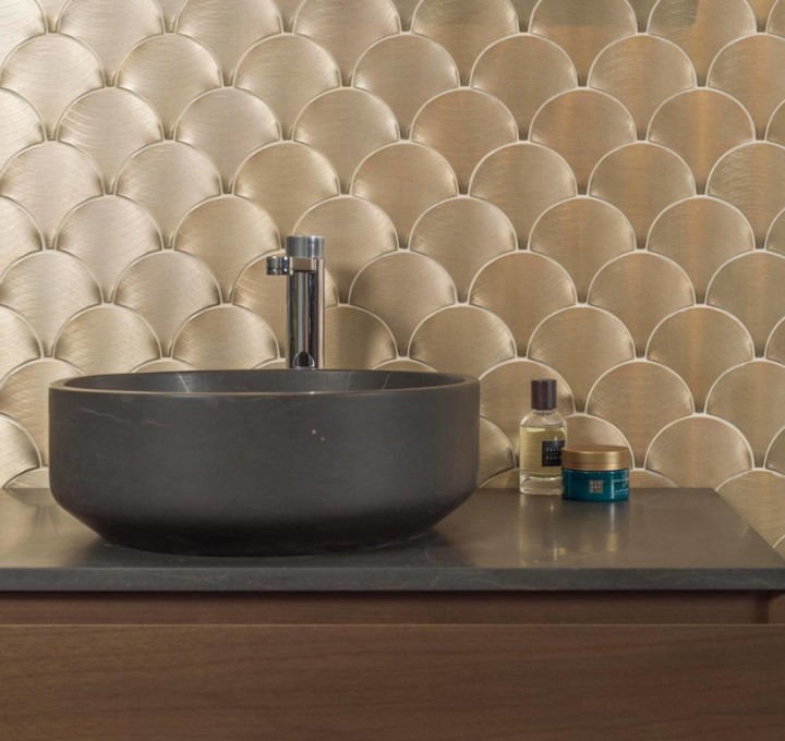 Gouden visschub-tegels als eyecatcher achter een ronde waskom in de badkamer